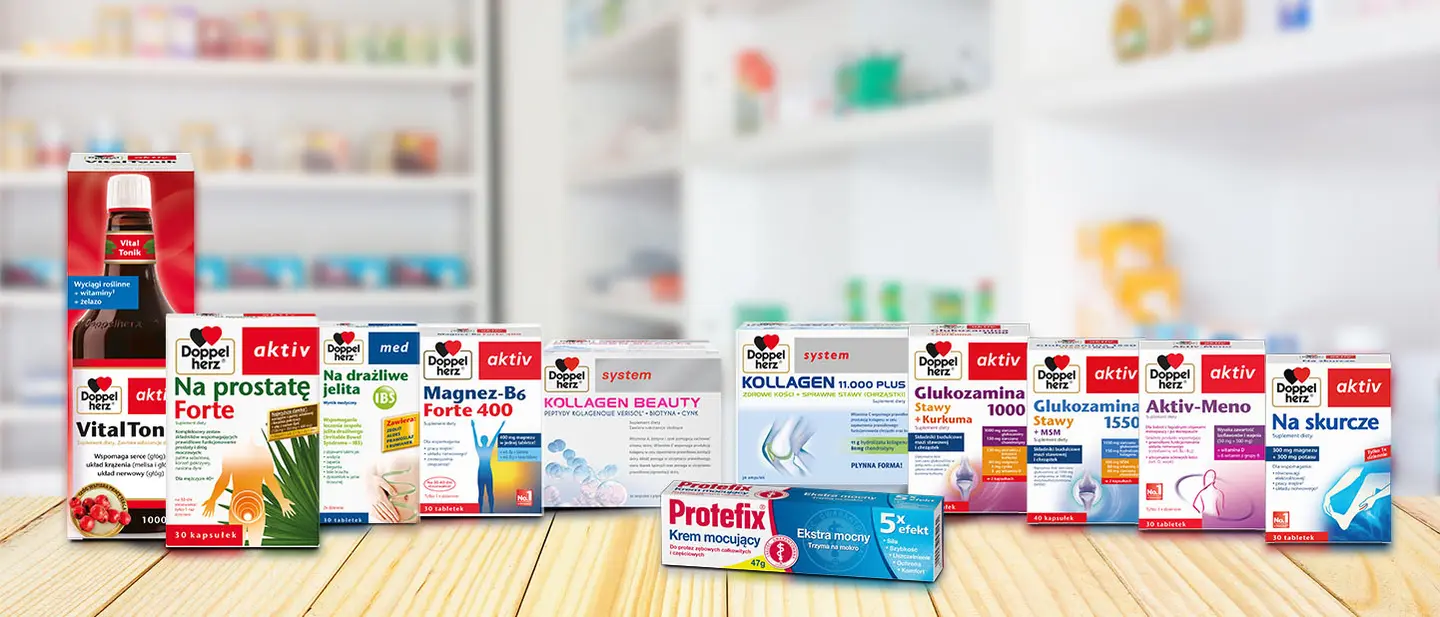 Na zdjęciu znajdują się opakowania suplementów diety marki Doppelherz. Widać różne produkty, takie jak VitalTonik, Kollagen, Glukozamina oraz suplementy na prostatę i dla kobiet w menopauzie, na drewnianym tle. W tle znajdują się szafki z innymi produktami.